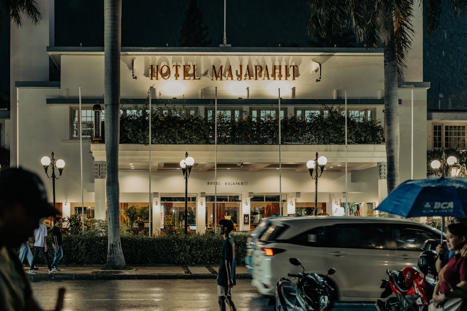Night view of the historic Hotel Majapahit in Surabaya, featuring street activity and vibrant lights.