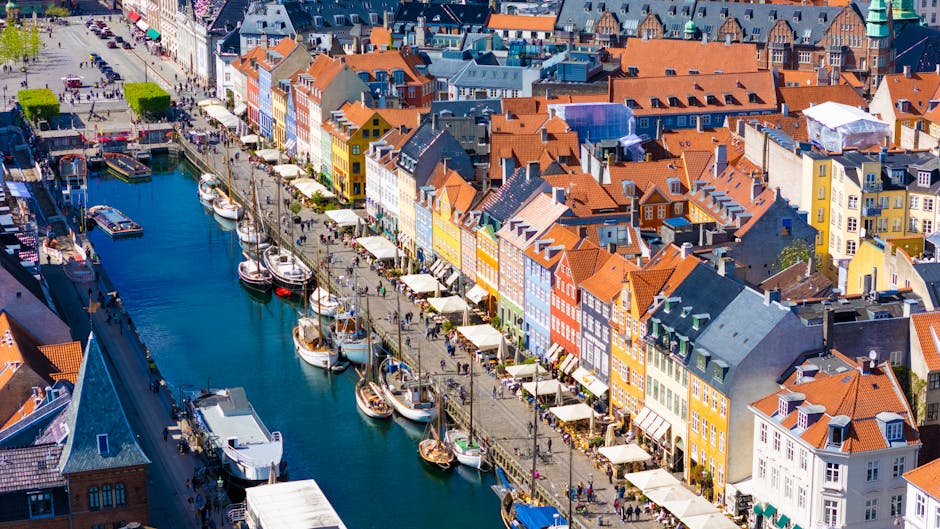 Vibrant aerial view of Nyhavn Canal in Copenhagen, showcasing colorful buildings and historic boats.