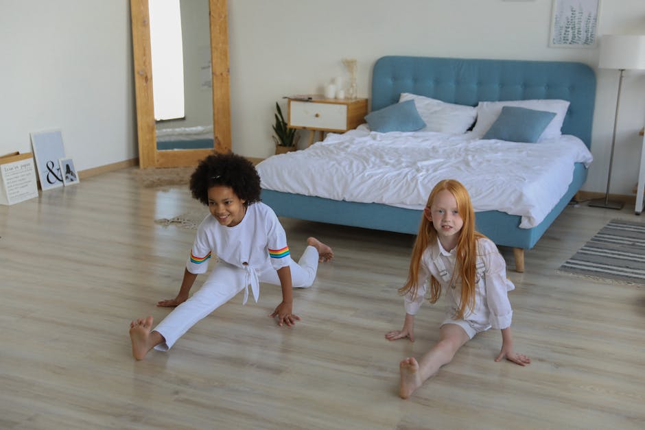 High angle of multiracial girls spending time at home and showing splits together on floor
